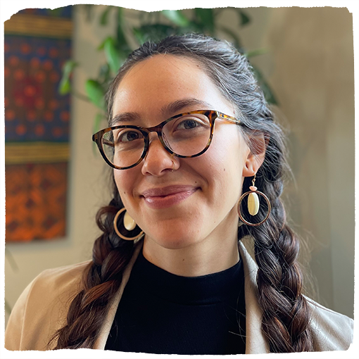 Alessandra de la Torre smiles at the camera wearing her hair in braids.