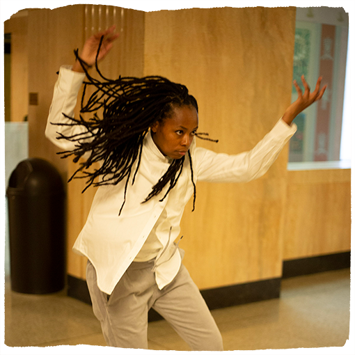 Intisar Abioto is caught mid-performance, arms raised in the air and her hair flowing wildly behind her.