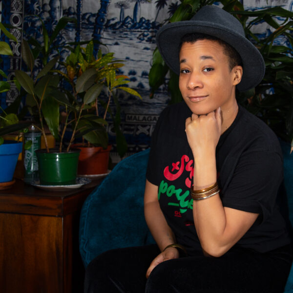 RaShaunda Brooks, in a hat, poses for a photo while sitting with her hand under her chin