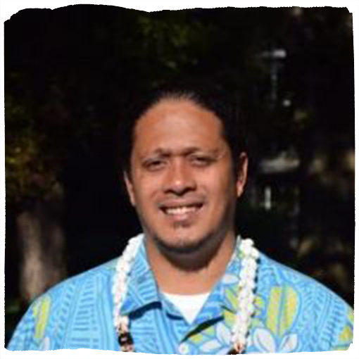 Makerusa Porotesano wears a sky blue hawaiian shirt and a white floral lei.