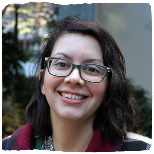 Camerina smiles at the camera wearing dark rimmed glasses and a red collared shirt.