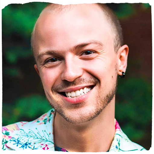 Damon Motz-Storey, wearing a floral print shirt, smiles into the camera.