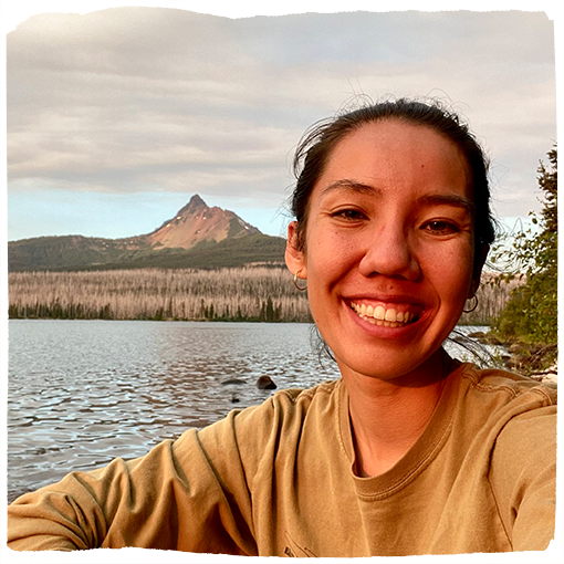 Rachel smiles in the setting sun in front of an alpine lake and Mount Washington in Central Oregon