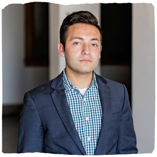Ramon stands wearing a blue checkered shirt under a navy blazer.