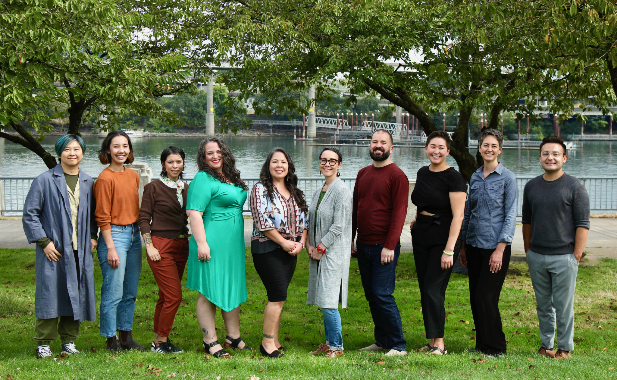 The Seeding Justice staff poses in front of trees along the Willamette River waterfront.